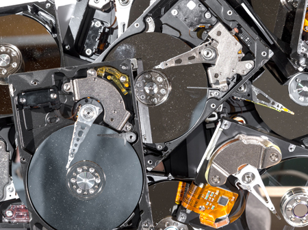 A pile of old computer hard drives which contain personal or business data that Green Ewaste Recycling Center can securely delete or physically destroy with Data Destruction